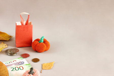 autumn sale layout on light background, shopping bag next to coins, orange yarn pumpkins and leaves,...