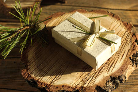 happy new year, gift in a white box on a wooden background next to a spruce branch.の写真素材