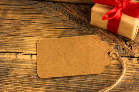 craft tag on a wooden background next to a spruce branch and a gift, congratulations.の写真素材