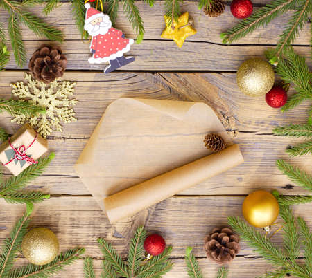 message on craft paper mockup in the center of a circle made of christmas decorations and branches of a christmas tree on a wooden background.の写真素材