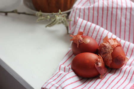 Easter eggs on a cotton napkin in the background. Eggs dyed with natural onions on a rustic white window background. Natural ecological coloring with food coloring. View from above.の写真素材