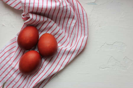 Easter eggs on a cotton napkin in the background. Eggs dyed with natural onions on a rustic white window background. Natural ecological coloring with food coloring. View from above.の写真素材
