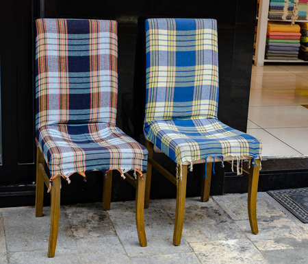 Rocking chair with a checkered plaid on the background of an old wall.