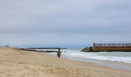 USA California Los Angeles Dockweiler State Beach May 22 2023 a woman walks on the beach with shoes...