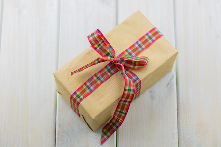 Box with a gift on a wooden table tied with red ribbon.の写真素材