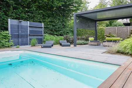 Appeltern, The Netherlands, July 22, 2015: The Gardens of Appeltern is the inspiration garden park in the Netherlands. In this picture a swimmingpool with outdoors shower, trendy sunloungers and overhang with trendy garden chairs.のeditorial素材