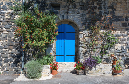 Blue door in the old wall of basalt, decorated with wild rose bushes.の写真素材