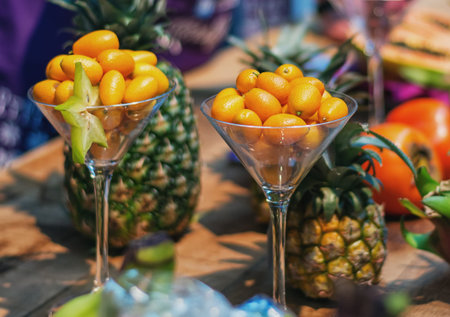 Dwarf orange als known as kumquats served in a glass with on the background pineapples
