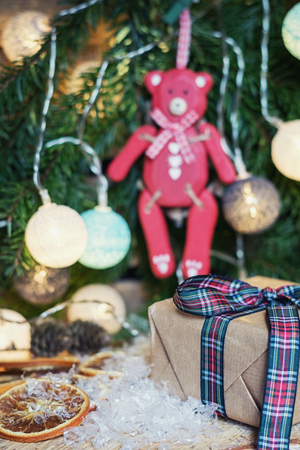 Red wooden bear hanging in Christmas branch decorated with illuminated christmas ballsの写真素材