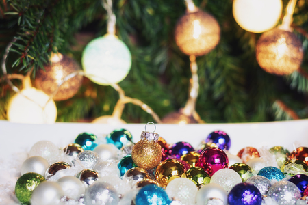 In a white box a collection of christmas balls in many colors with in the background a Christmas branch decorated with christmas ballsの写真素材