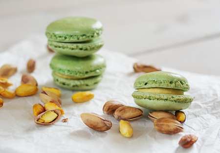 Peeled and unpeeled pistachio nuts  and pistachio flavored macarons presented on a white napkin presentedの写真素材