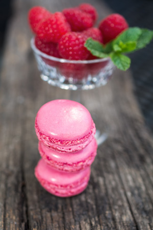 Delicious macarons raspberry flavored with a glass filled with fresh raspberries with a sprig of mintの写真素材