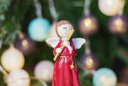 Angel with flute in front of a Christmas branch decorated with christmas ballsの写真素材