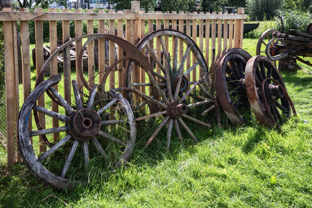 Old and broken wagon wheels against a fenceのeditorial素材