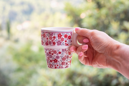 Cheerful cup with coffee in the hand of a woman with pink nail polishの写真素材