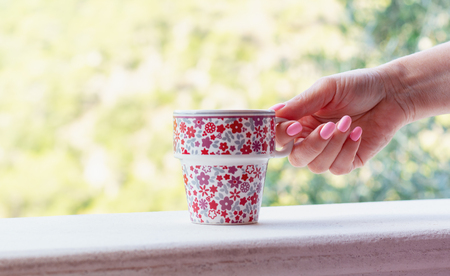 Cheerful cup with coffee in the hand of a woman with pink nail polishの写真素材