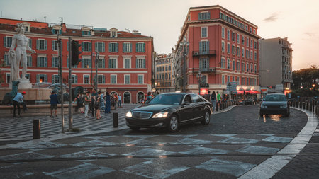 Nice, France, September 20, 2018:  Cars pass the Fountain of the Sun on Place Massena in the center...
