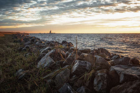 The dike around the island of Marken in the Netherlands during sunrise with the lighthouse Het Paard van Marken in the backgroundの写真素材