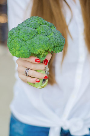 Fresh and big broccoli harvest. The girl holds the crop in his hands.