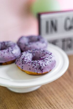 Delicious sweet donuts with purple icing lie on a white plate. Unhealthy and tasty foodの写真素材
