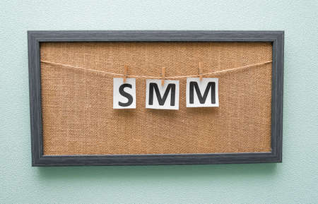 letters smm on white background are written on pieces of paper attached with clothespins to boardの写真素材