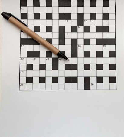 pen made of recycled material lies on empty crossword puzzles top view free space isolatedの写真素材