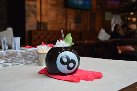 cocktail in a black billiard ball on a pink in a bright restaurant isolated