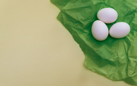 white eggs on green silk on a yellow backgroundの写真素材