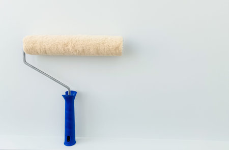 girl paints the wall with white paint. female hand with wall paint roller close up with copy space