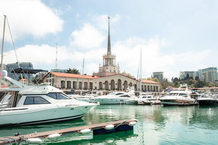 Motor ships and yachts on the pier in front of the Marine Station. Close-up. Calm Black Sea. Sea trade port with mooring boats at sunset in Sochi, Russiaの写真素材