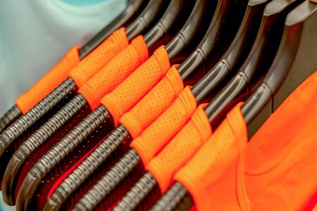 an orange sports clothing on hangers in a shop, abstract backgroundの写真素材