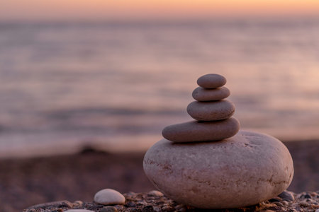 Perfect balance of stack of pebbles at seaside towards sunset. Concept of balance, harmony and meditation. Helping or supporting someone for growing or going higher up.の写真素材