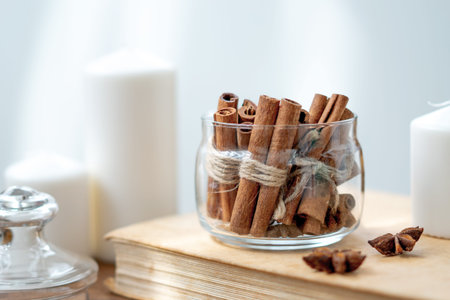 Cinnamon sticks in glass jar, anise star, candles, vintage book on old rustic rustic wooden...