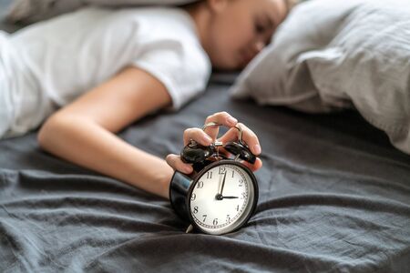 Woman with insomnia lying in bed with her head under her pillow trying to sleep. Insomnia and sleep problems. Relax and sleep concept. Feels sleepy and tired.の写真素材