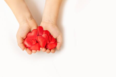 Close up of child hands holding red hearton white background - people, love, charity and family conceptの写真素材