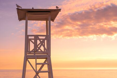 Sunset on the beach with lifeguard tower and colorful cloud and blue sky.の写真素材