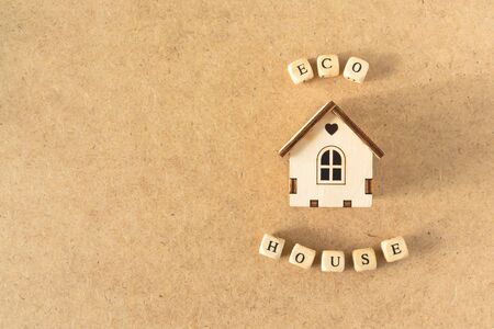 Eco friendly house - small toy model house with inscription word ECO HOUSE on kraft cartboard bacground. Zero waste, recycle, sustainable living, recycle, green house conceptの写真素材