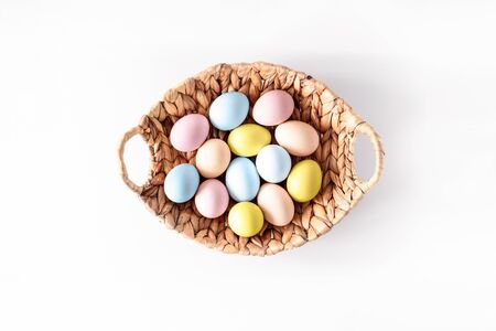 Colorful eggs in a basket on white background. Natural healthy food and organic farming, easter and spring concept.の写真素材