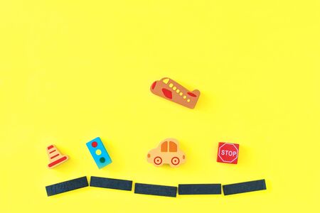 Colorful baby kids wooden toys on yellow background. Developing colorful blocks, cars and airplane. Top view. Flat lay. Copy space for textの写真素材