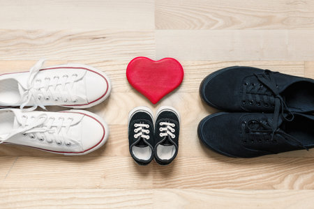 Happy family concept. Father, mother and little kid shoes on wooden floor