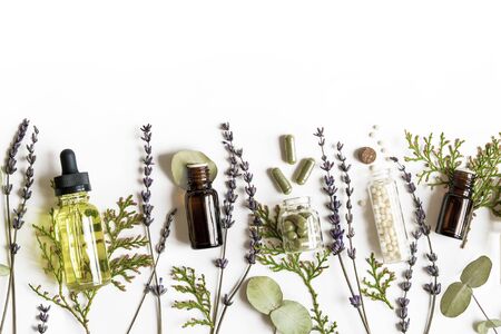 Homeopathy eco alternative medicine concept - classical homeopathy pills, thuja, eucalyptus, lavender essential and aroma oil and healing herbs and on white background. Flatlay. Top view. Copyspaceの写真素材