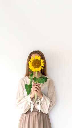 Beautiful young woman in linen dress holding sunflowers bouquet on white background. Autumn concept.の写真素材