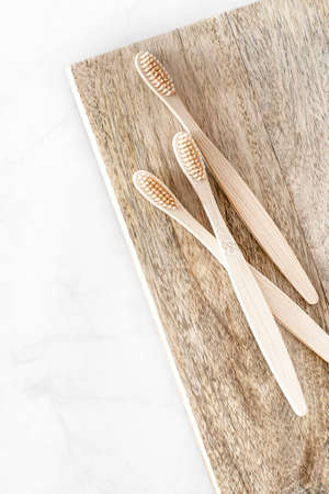 Composition with biodegradable bamboo toothbrushes on wooden background. Sustainable, zero waste, plastic free, lifestyle concept. Eco-friendly oral hygiene accessories.Flat lay, top view, copy space.の写真素材