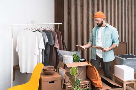 Mature man unpacking things from boxes while moving in new unfurnished apartment.の写真素材