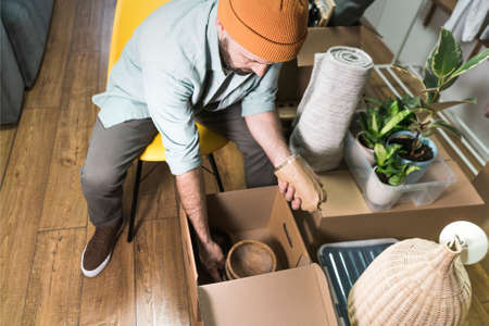 Mature man unpacking things from boxes while moving in new unfurnished apartment.の写真素材