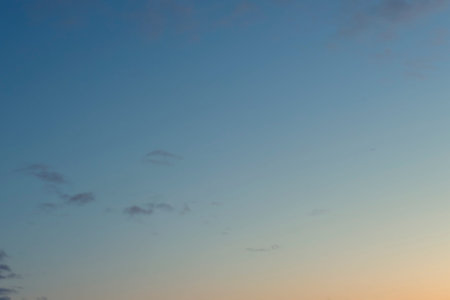 Gradient sunset sky with a few small gray clouds. Nature background image