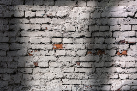 Old brick wall plastered and colored with white paint. Background image with shadows. Peeling paint