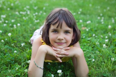 The little girl lies on a lawn and smiles.の写真素材