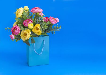 Bouquet of flowers in a paper bag on a blue backgroundの写真素材