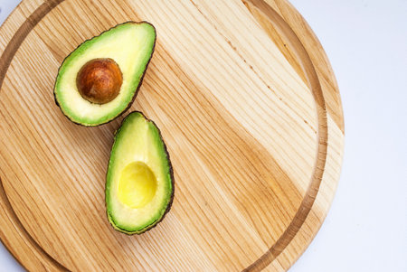 Sliced â€‹â€‹avocado with bone close-up on a wooden background. Empty space for text.